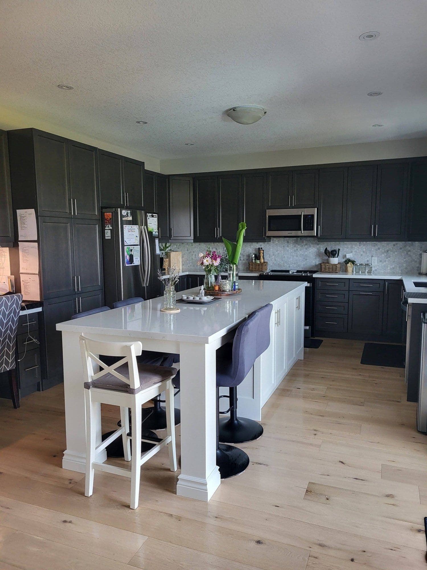 Open-concept kitchen with dark cabinetry, white island, and hardwood floors