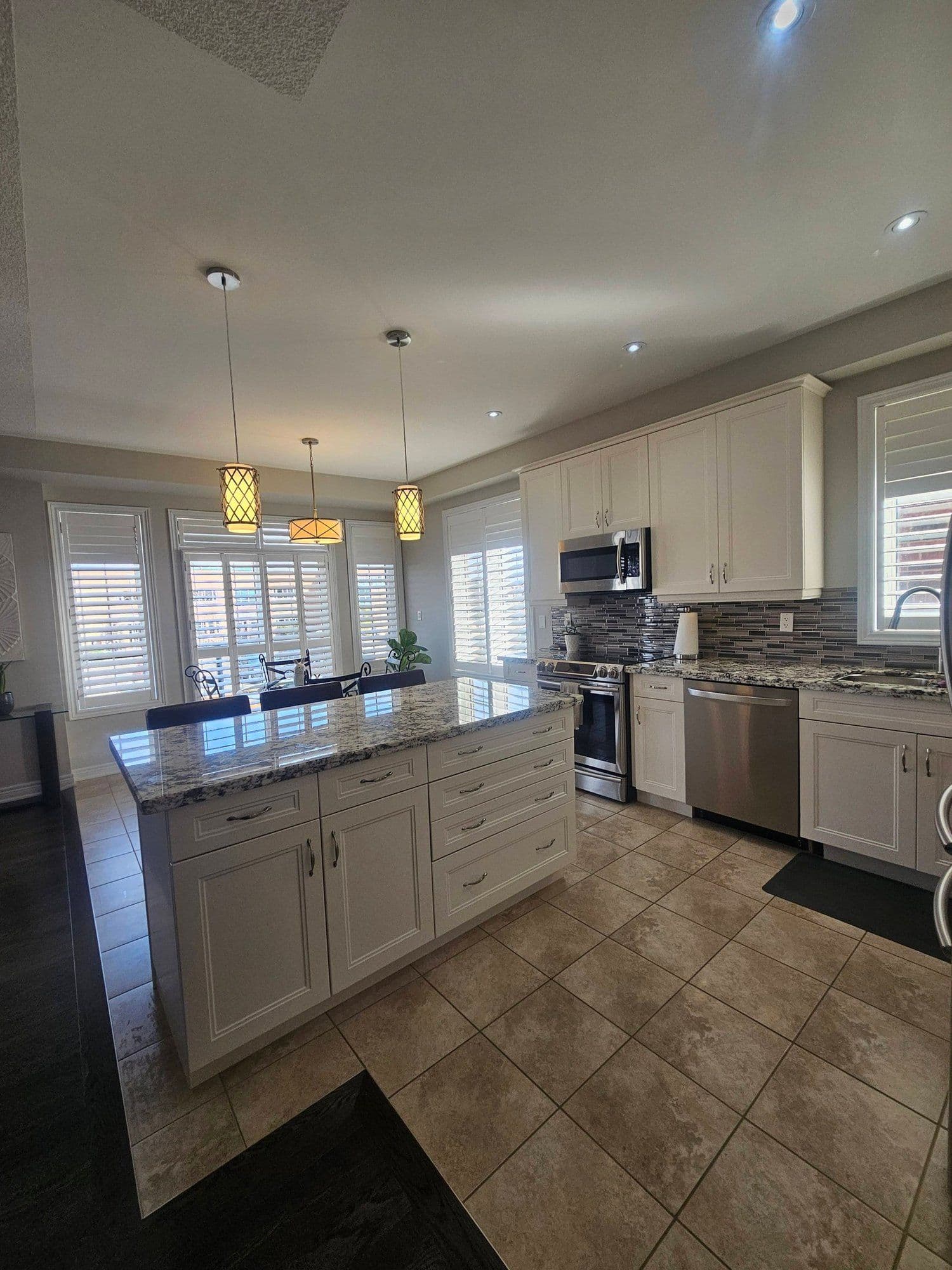 Bright white-cabinet kitchen with granite island and pendant lighting