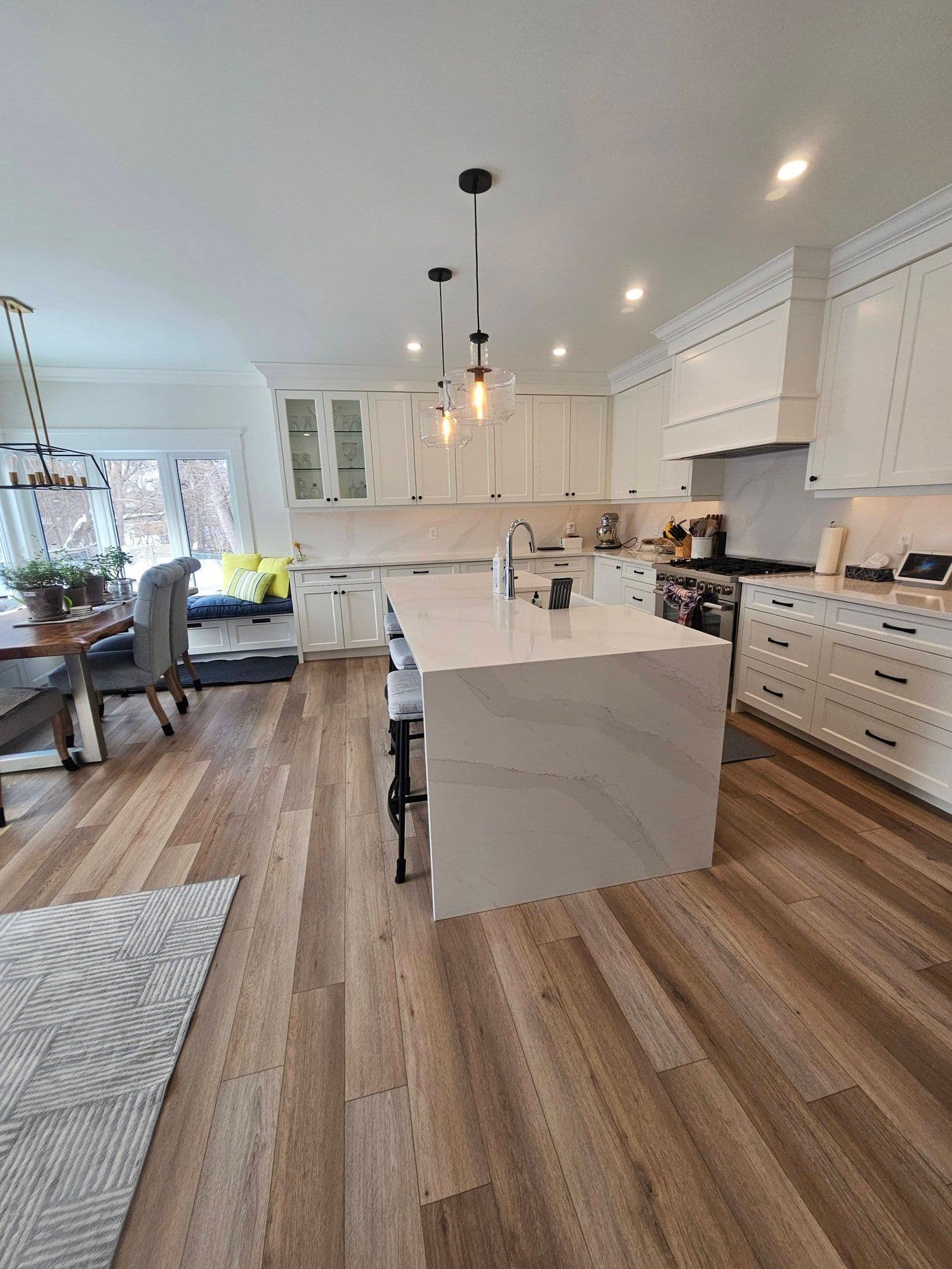 Luxury kitchen with marble waterfall island, white cabinets, and pendant lighting after a Luxury Estate Cleaners service