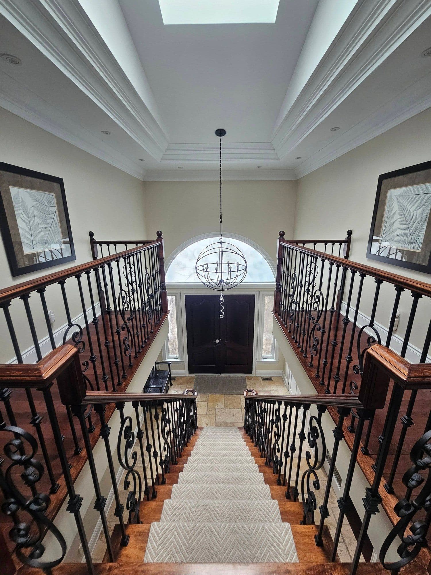 Staircase landing with wrought-iron railings and orb chandelier