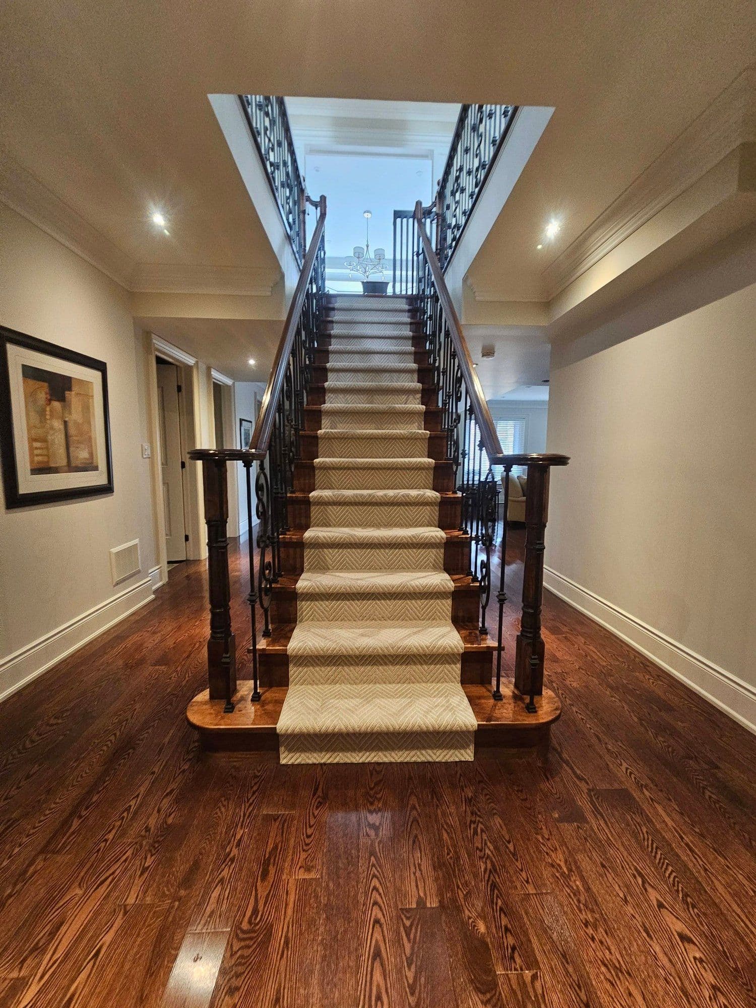 Hardwood staircase with patterned runner and wrought-iron railings