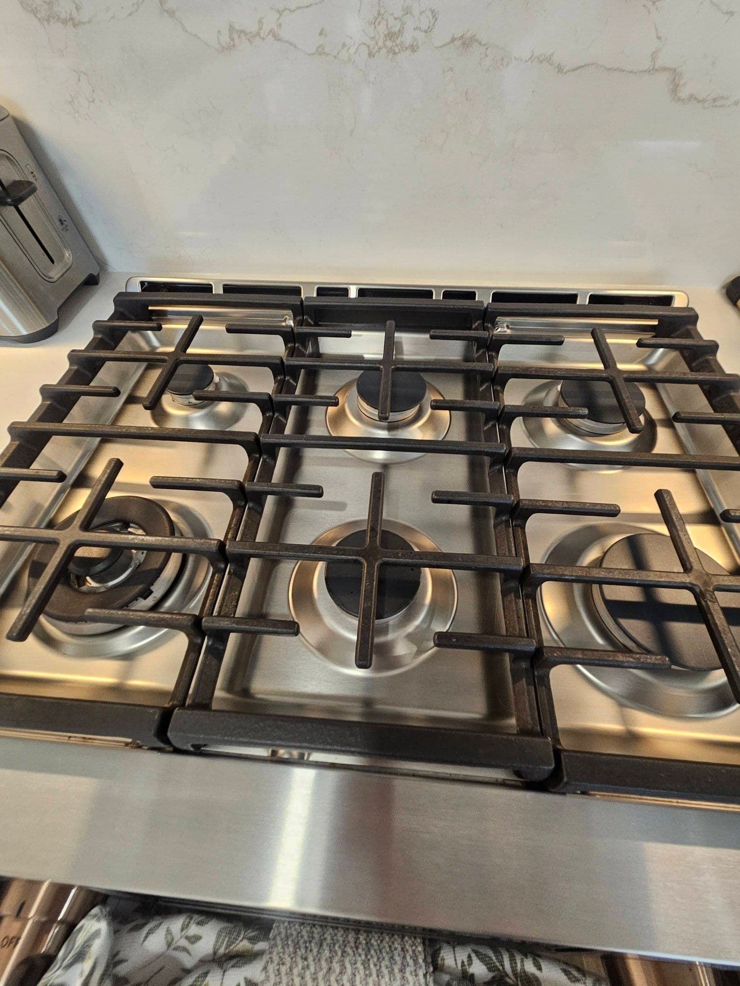 Stainless gas stovetop and quartz backsplash, polished spotless